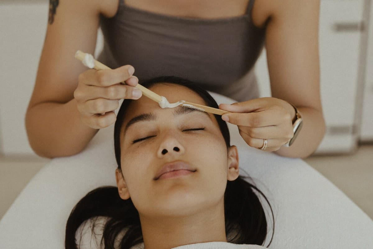 Augenbrauen-Waxing in Berlin – warmes Wachs wird mit dem Spatel aufgetragen